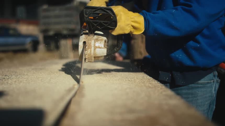 Person uses powered saw to cut wood