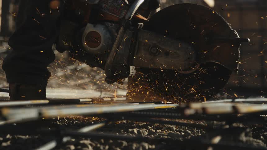 A person cutting metal with a big saw