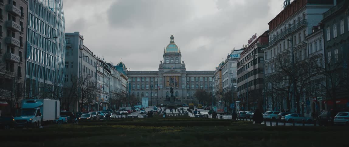 Pedestrians and traffic move between buildings with domed building in the background