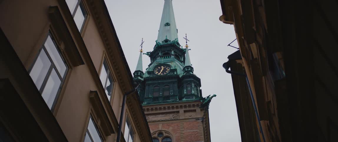 A clock tower rests between two apartment buildings