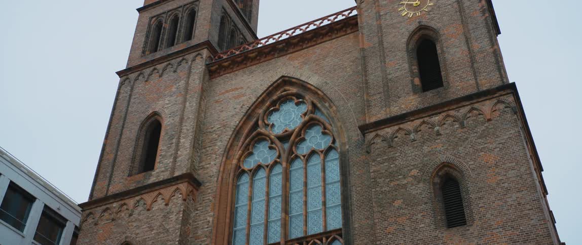 View of the bell towers, gothic windows, and front facade of Friedrichswerdersche Kirche museum in Berlin, Germany