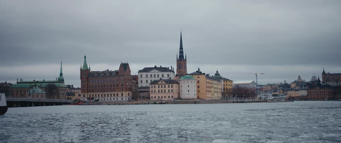 Ice floats on the river next to the city under a cloudy sky