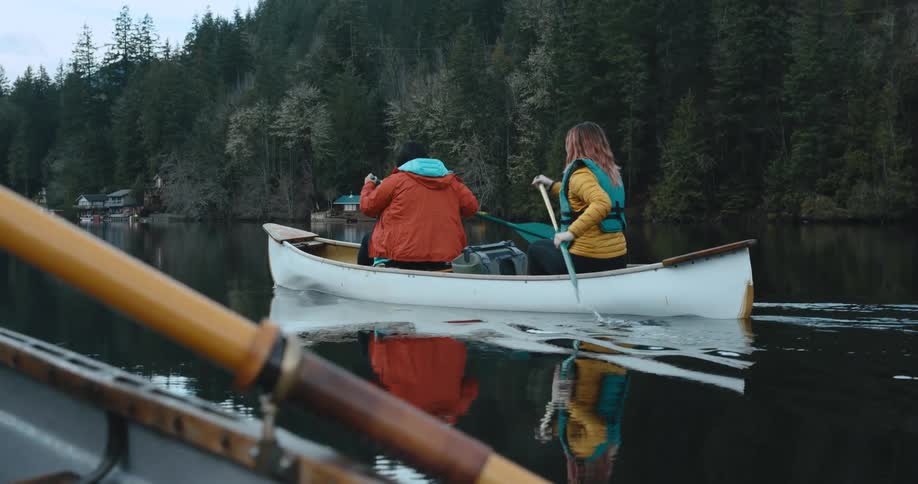 Two people paddling in a white canoe along the river in the mountains
