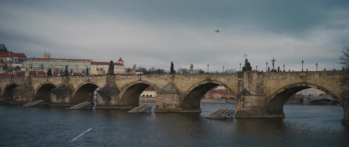 View of the medieval arched Charles Bridge over the River Vltava in Prague, with many statues adorning each side of the bridge.