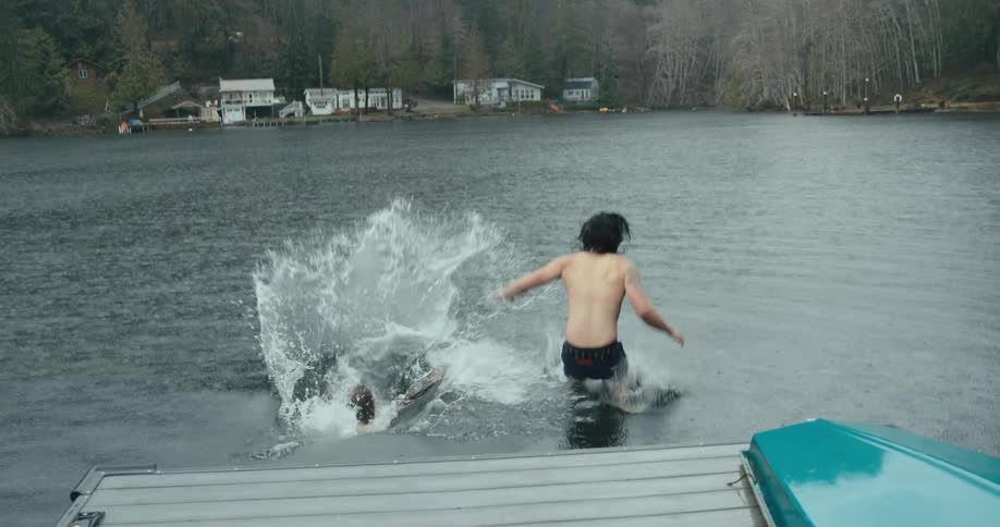 Two people running off a pier into a lake