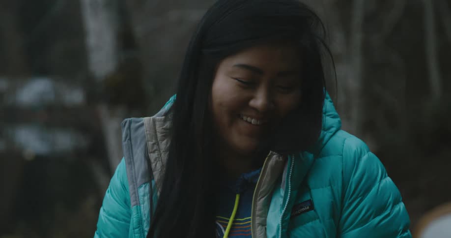 A woman laughs as she blows out the flames on her blackened marshmallow