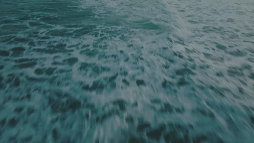 Aerial view of foamy ocean waves breaking against the beach