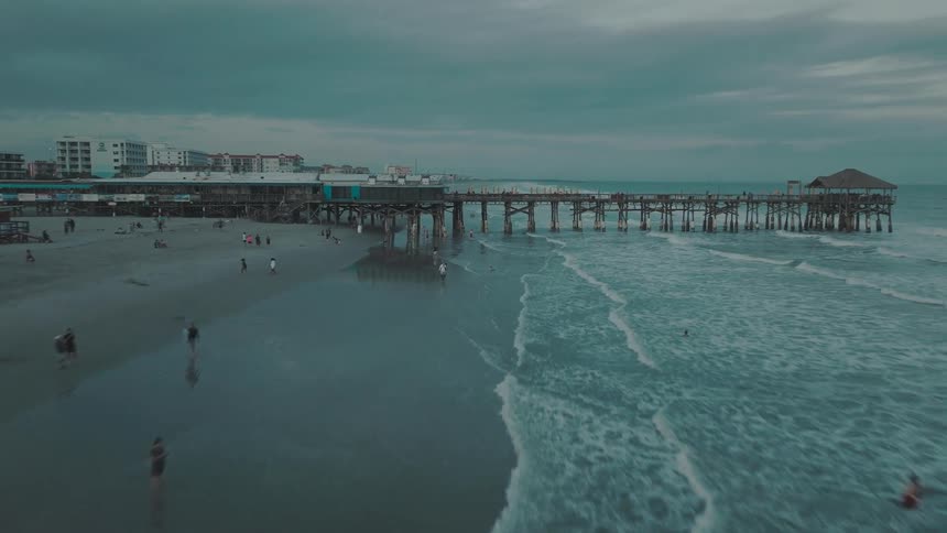 An aerial view of people on the beach and in the water as waves roll in