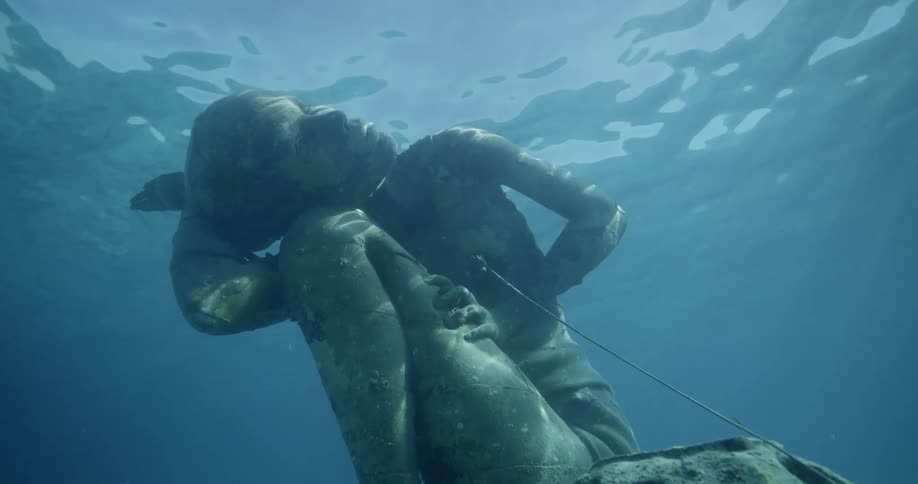 The sun shines on statue of man underwater