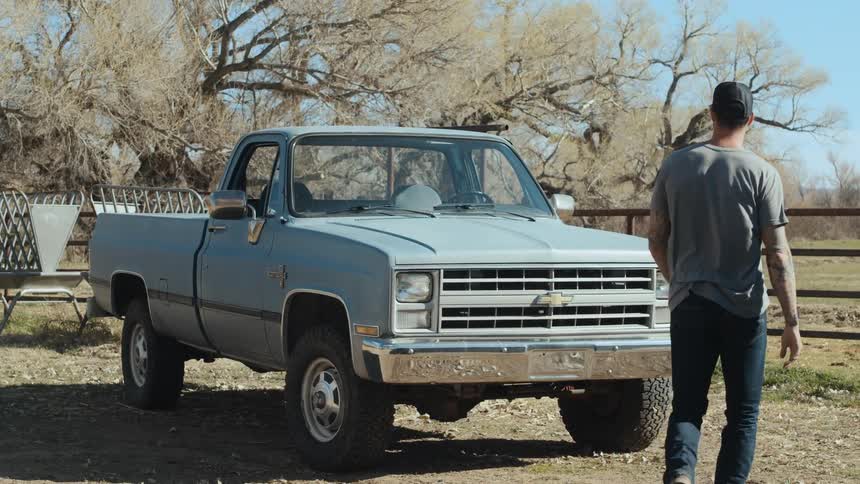 A man in a rural area walks towards a truck