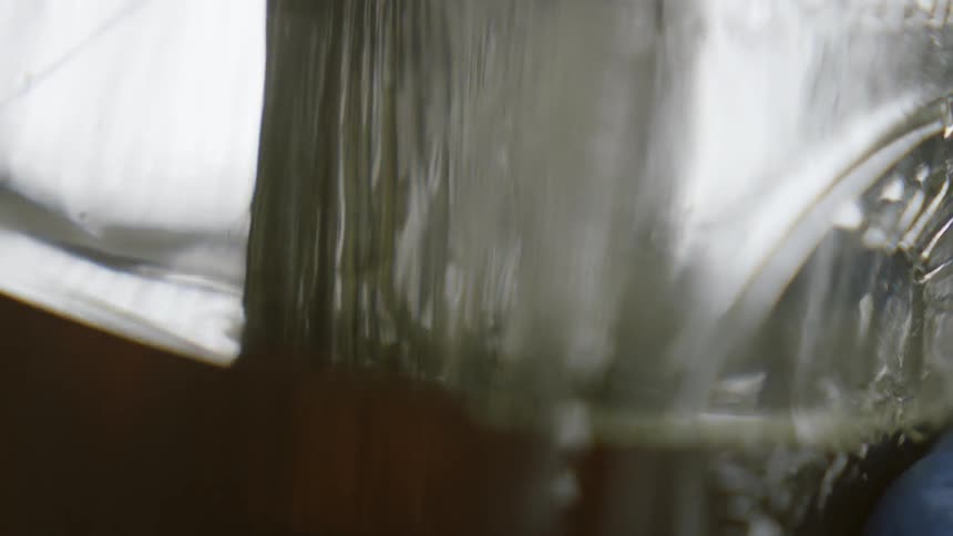 A person dips a brush into brown liquid