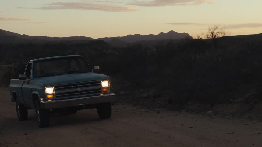 A man drives his truck down a dirt road in a rural area