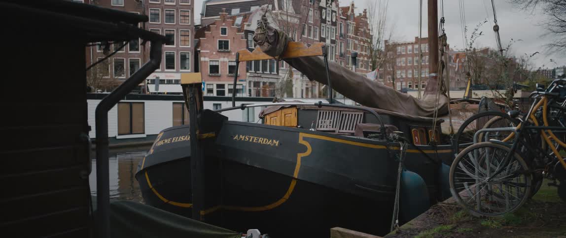 Bikes parked near a houseboat on a canal in Amsterdam