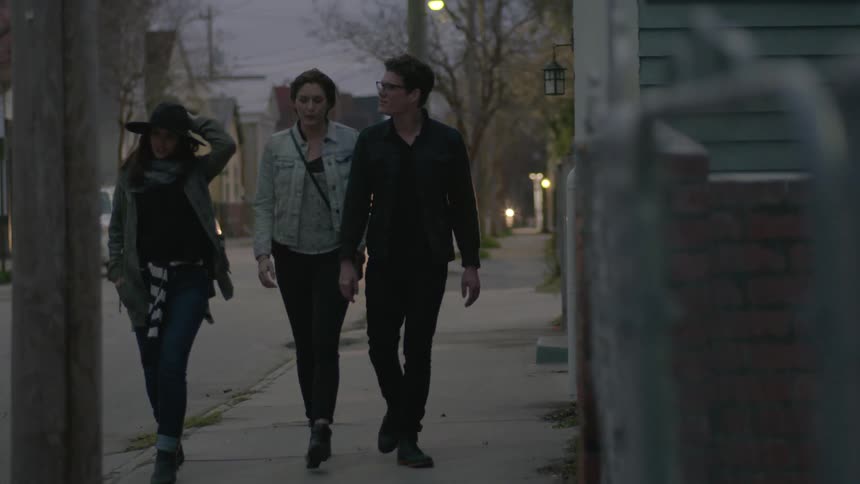 Three young adults walking down a city street