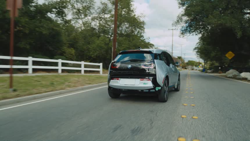 An electric car is traveling on a neighborhood street