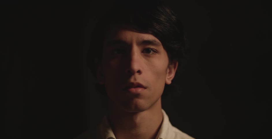 Man staring blankly forward with a dark background