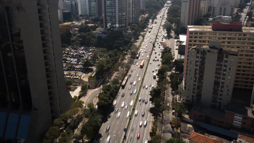 Cars traveling on a busy city street surrounded by skyscrapers