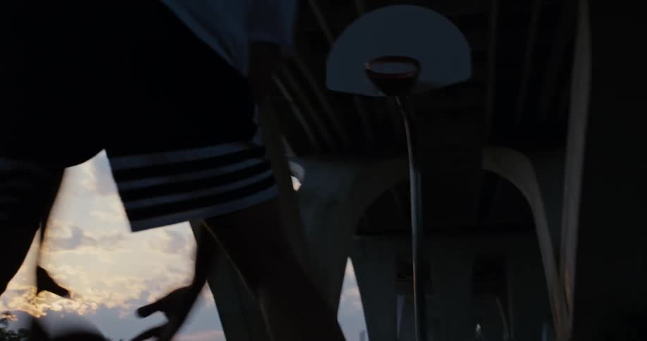 A man playing basketball on an outdoor court at sunset