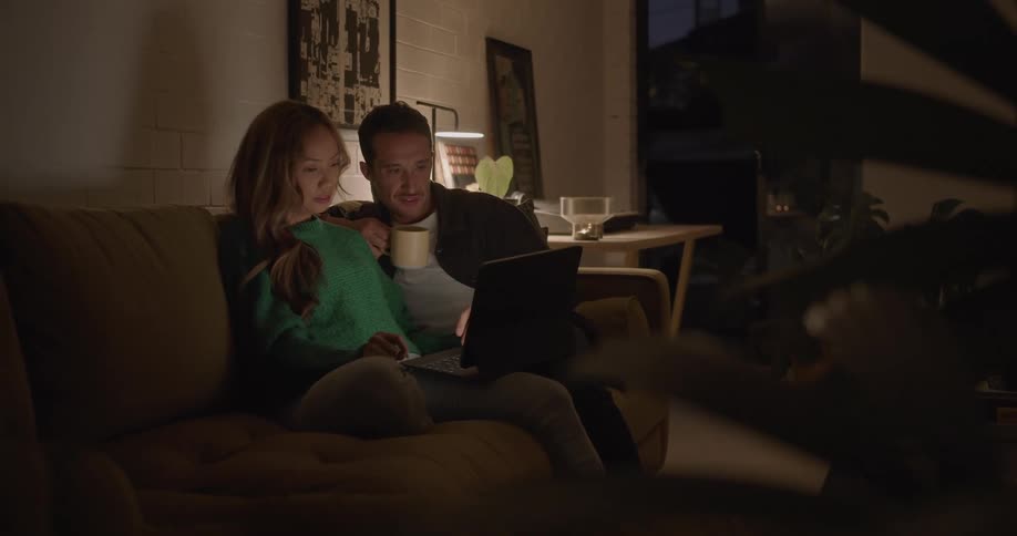 A couple watch a video together on the couch