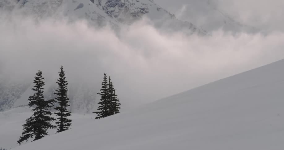 Clouds floating through a snowy mountain range in winter