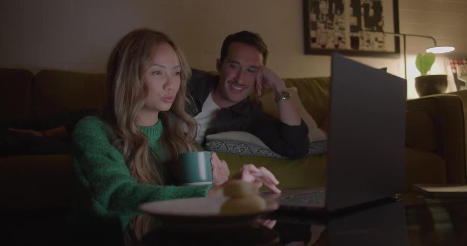 A man and woman look at a laptop at home