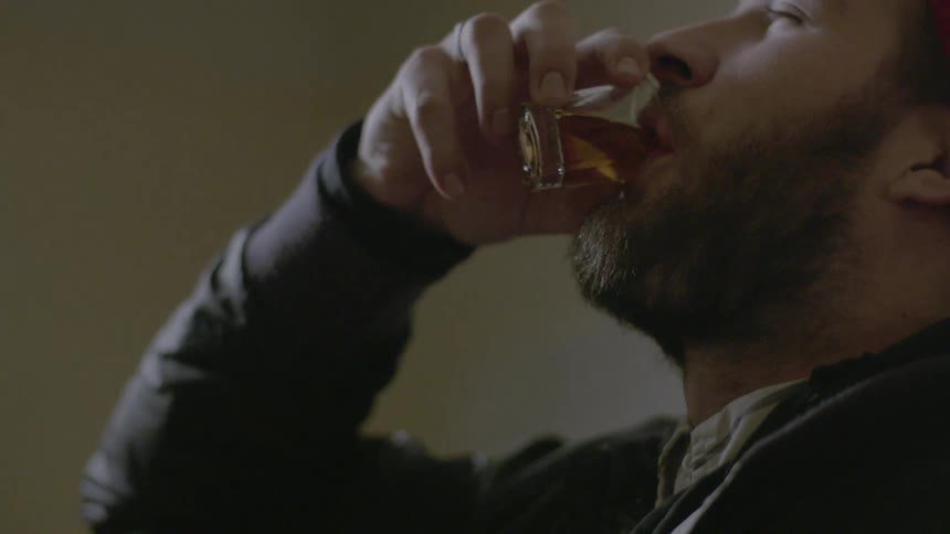 Bearded man drinking a shot of liquor