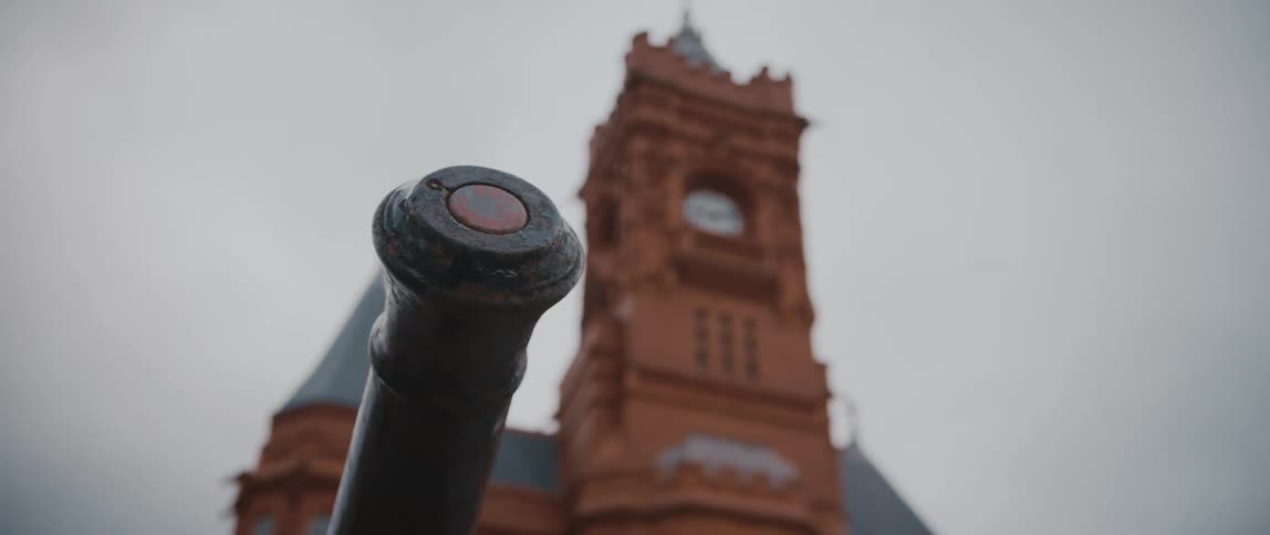 An iron pole sits in front of a clock tower