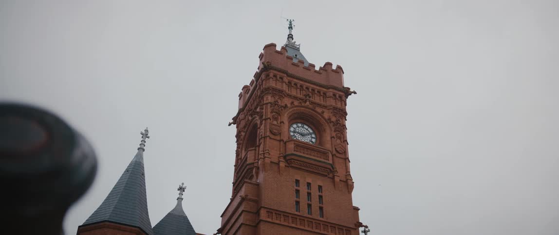 Clock tower stands over narrow pointed roofs