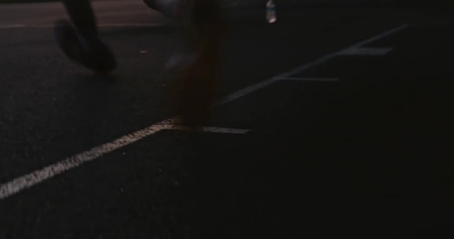 Man sweeps up basketball and jumps to sink basket before hanging off hoop standing under overpass as fog covers mountains and forest on the horizon