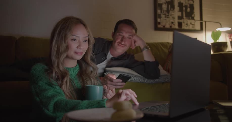 A man and woman look at a laptop together