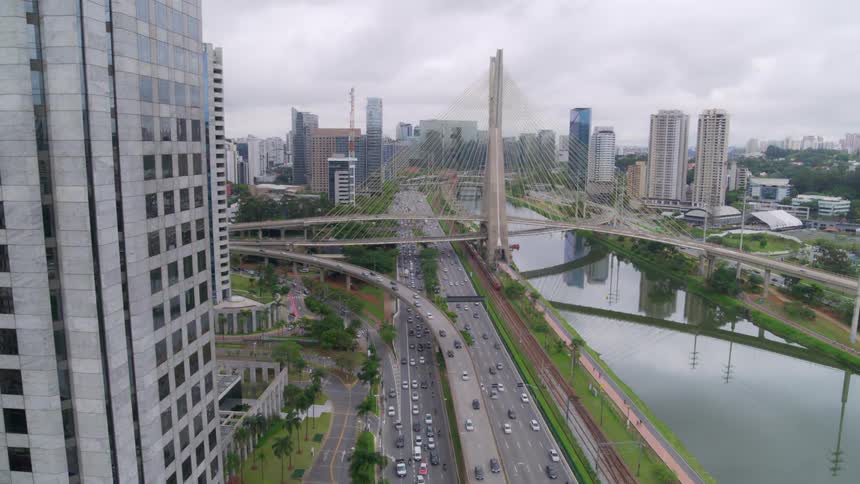 Traffic moves past the city highway with cable-stayed bridge in the back