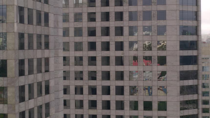 Skyscrapers with many windows next to a river in a city with cars traveling on the road
