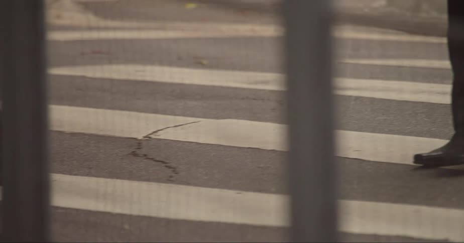 People wearing business suits cross street at the crosswalk