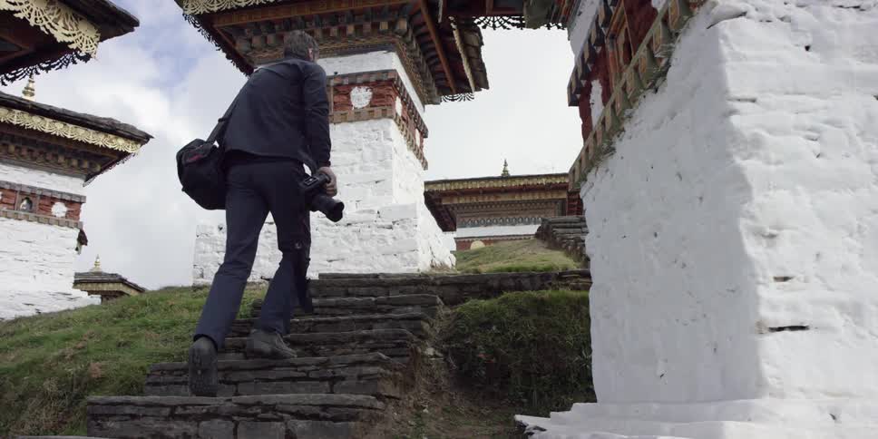 A man walks up steps towards a temple