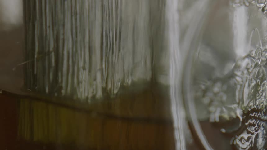 A brush is being dipped into a glass container
