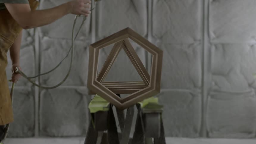 Man spray painting pieces of wood