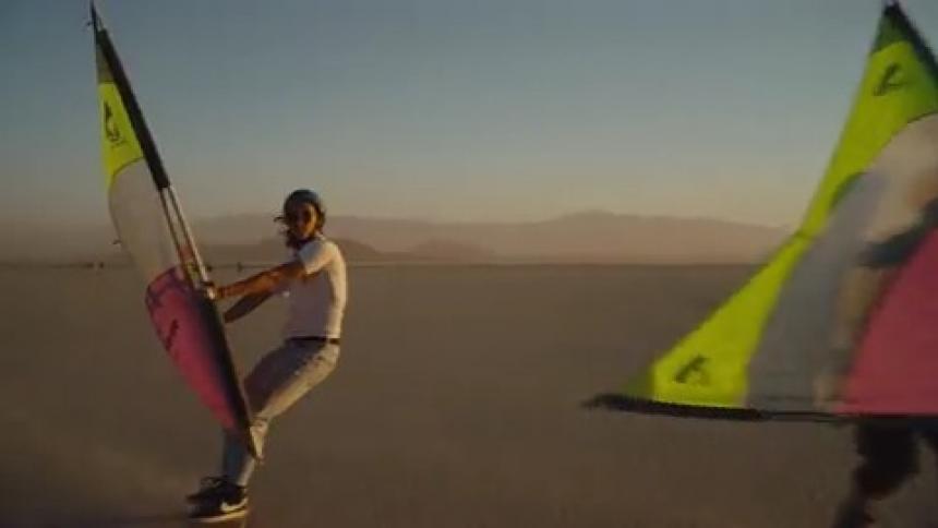 A group of people land sail through the desert