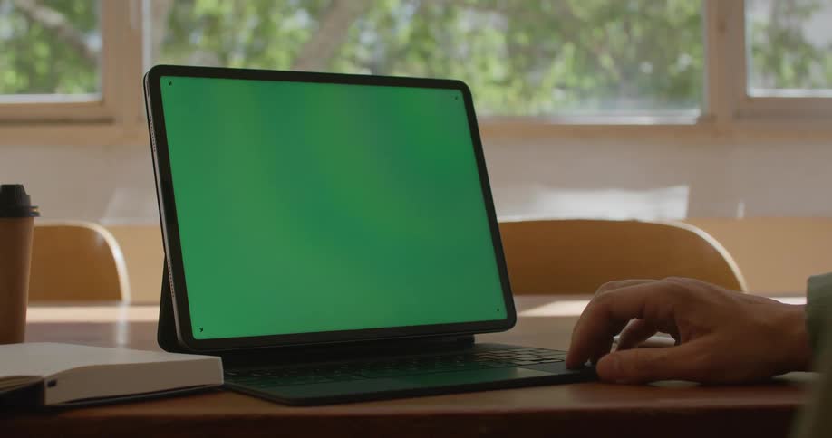 A person using a tablet while sitting at a table
