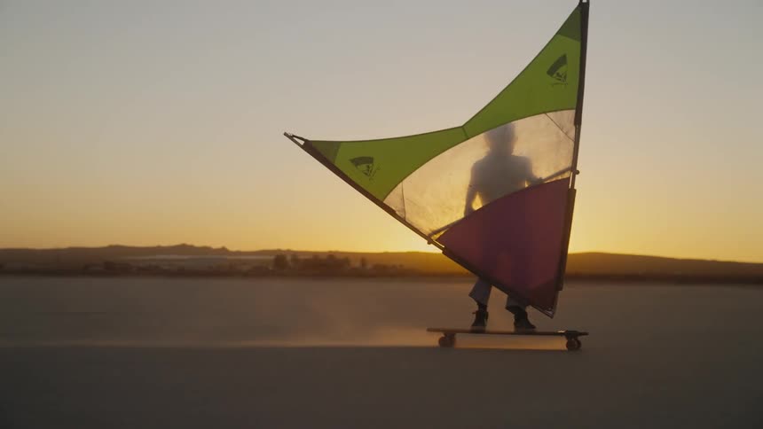 A man speeds over a salt flat on a wind-powered skateboard