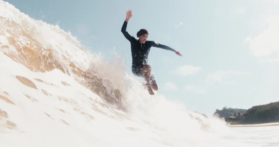 A surfer is riding a wave and goes underwater as he tries to stand on his surfboard