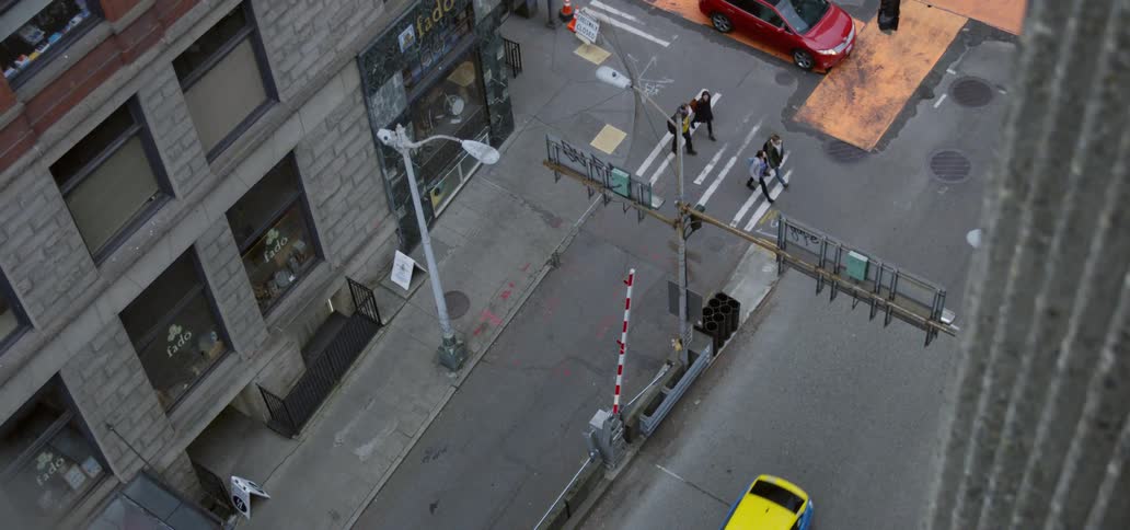 Pedestrians cross intersection at cross walk as taxi takes turn