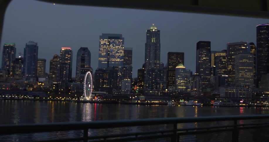 Illuminated skyscrapers and ferris wheel seen from moving boat at night
