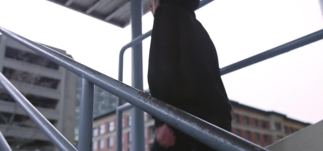 Woman wearing a hoodie and climbing the stairs in the middle of a big city