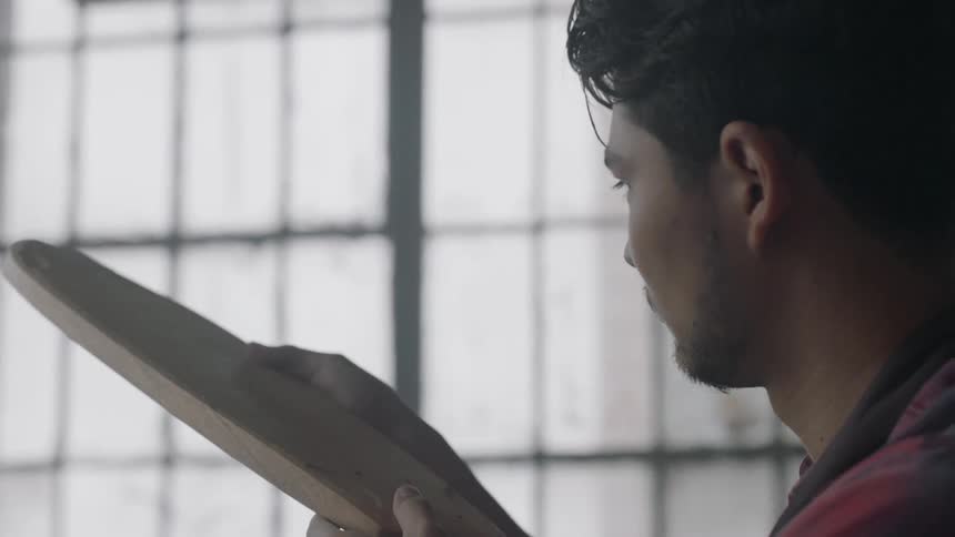 Man examines a piece of wood indoors