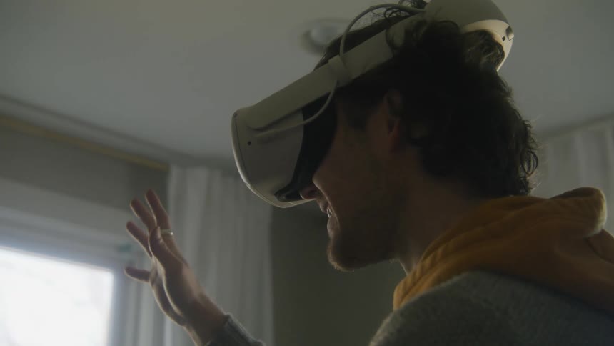 A man smiling while using a virtual reality headset at home