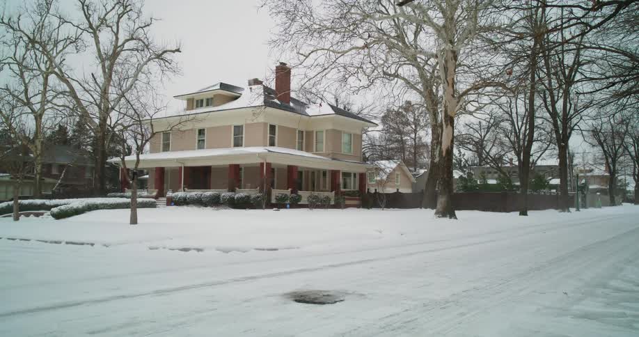 An automobile travels on a snow covered neighborhood street on a winter day