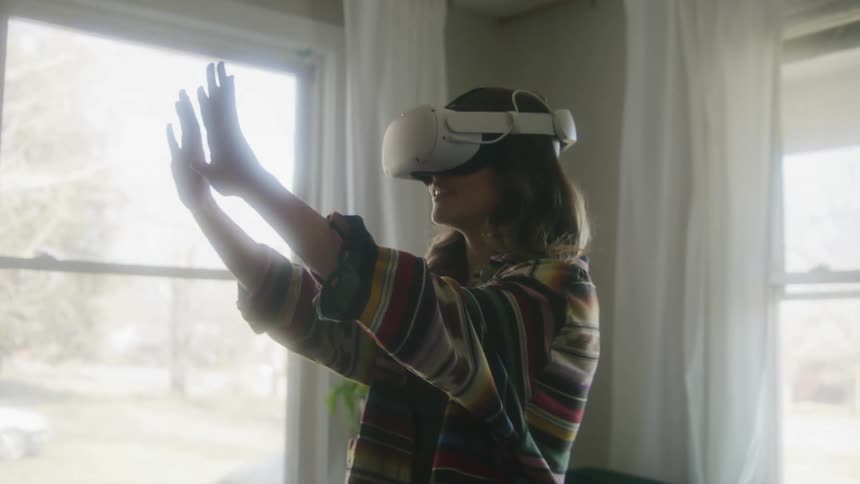 Woman with brown hair equipped with a vr headset uses virtual reality in living room at home