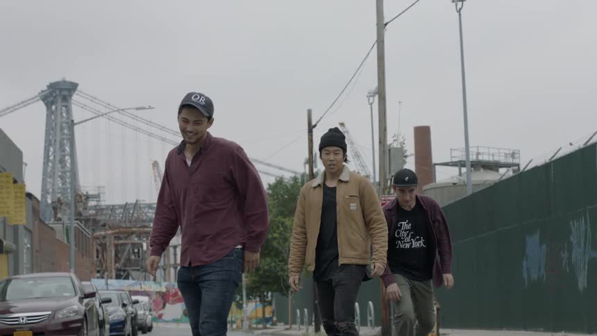 Four people skateboard past a parked motorcycle
