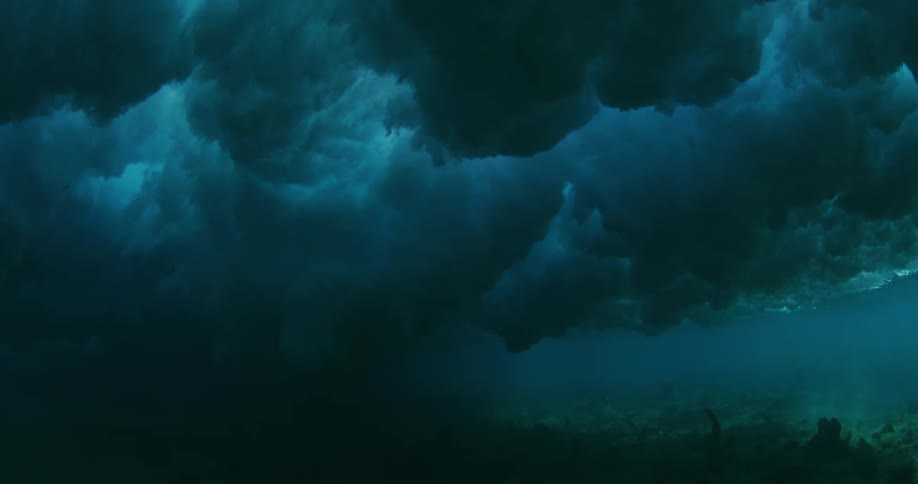 Powerful ocean waves are seen above from underwater near the ocean floor