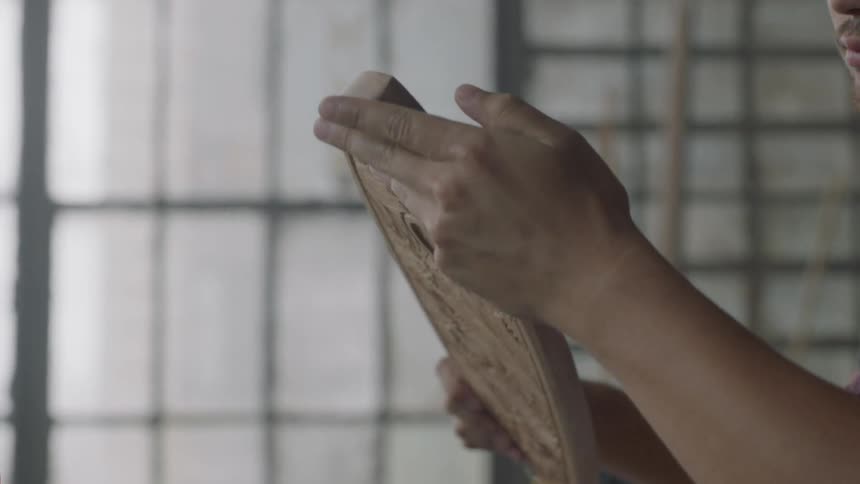 Man inspecting a freshly carved piece of wood